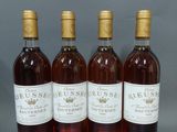 quatre bouteilles de vin sont alignées sur une surface grise