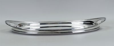 une assiette en argent avec un manche incurvé, posée sur une table