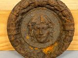 une plaque en bois sur laquelle est représenté un visage, à côté d'une autre plaque en bois