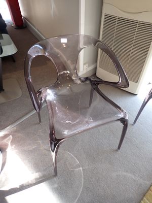 une chaise en plastique transparent posée au milieu d'un salon