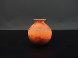 un vase orange posé sur une table noire