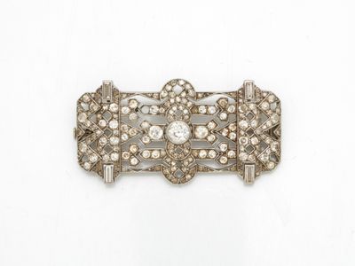 un gros plan d'une broche en diamant et argent sur fond blanc