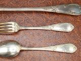 three silver spoons and two silver spoons on a table