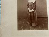 an old black and white photo of a woman in a dress and bonnet
