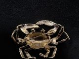 a close up of a gold crab broochle on a black background
