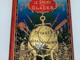un vieux livre posé sur une surface blanche, avec une couverture rouge et un globe doré
