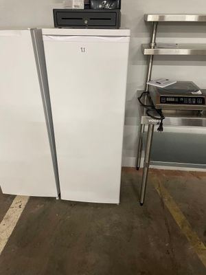 two white refrigerators in a room next to a chair