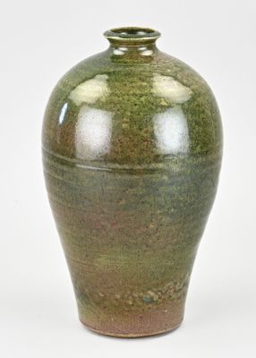un vase vert posé sur une surface blanche