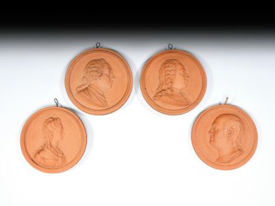 three bronze medallions with portraits of people on them hanging on a wall
