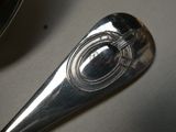 une cuillère en argent avec un manche en métal posée sur une table