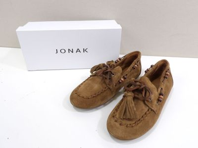 tan sued moccali shoes with tassels and a box on a white surface