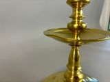 a gold plate with a candle on it in front of a window