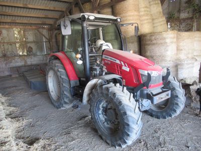 a red tractor that is parked in a barn