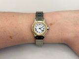 someone is wearing a watch on their wrist on a white table