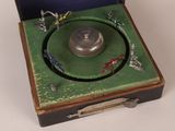 a small green box with a silver object inside of it