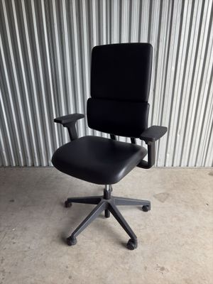 an image of a black office chair in front of a corrugated wall