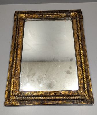 un miroir à cadre doré posé sur une table blanche, devant un mur blanc