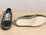 pair of black sneakers with white laces sitting on a wooden surface