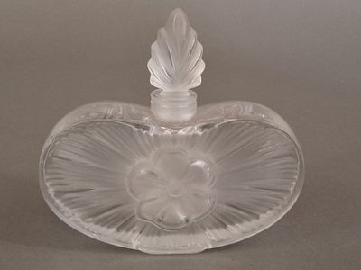 a clear glass heart shaped bottle with a leaf on it