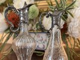 deux vases posés sur une table, avec des fleurs en arrière-plan