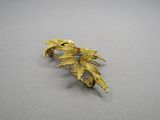 an image of a gold leaf broochle with a red bead
