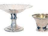 two silver vases sitting next to each other on a white surface