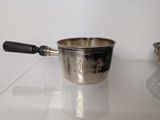 a silver saucepan and a silver bowl on a glass table