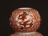a red and white vase with a dragon design on it