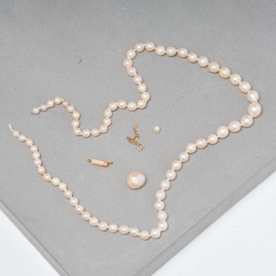 ensemble composé d'un collier et de boucles d'oreilles en perles, posé sur un fond gris