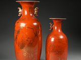une paire de vases orange ornés de motifs sur fond noir