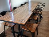 a long table with four chairs around it and a couch in the background