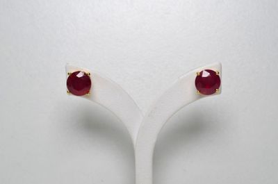 une paire de boucles d'oreilles à clous ornées de pierres rouges, posée sur un présentoir blanc