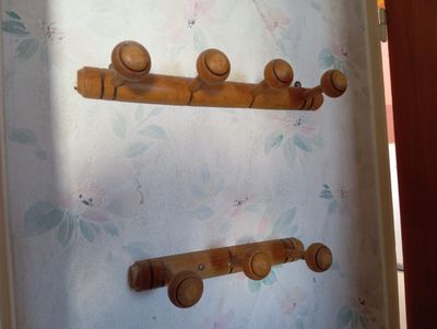 trois crochets en bois accrochés à un mur sur fond fleuri