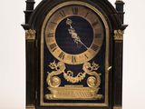 une horloge noire et or posée sur une surface blanche