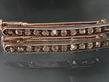 broche en forme de losange marron et blanc sur un fond noir