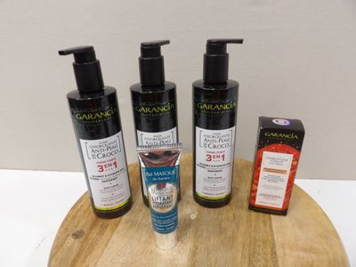 three bottles of olive oil and two packages of soap on a wooden tray
