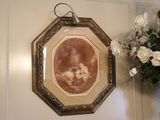 un tableau accroché au mur à côté d'un vase de fleurs