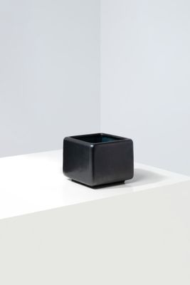 un vase carré noir posé sur une table blanche