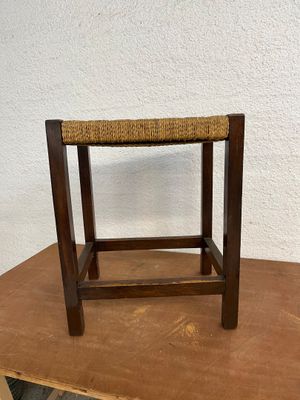 un tabouret en bois posé sur une table près d'un mur