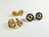 three pairs of gold and black earrings on a white surface