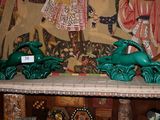 deux statues vertes représentant des animaux, posées sur une étagère devant un tableau