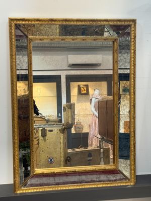 un miroir accroché au mur dans lequel se reflète une femme en robe rose