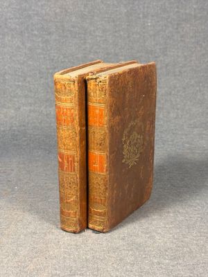 two old books sitting on top of each other on a table