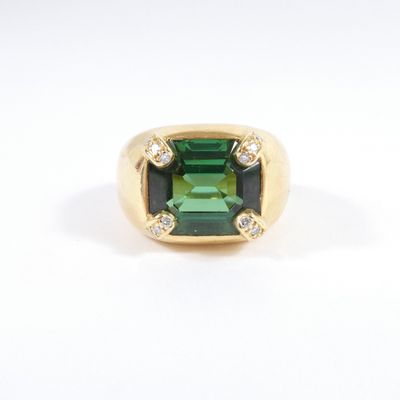 a close up of a green tourmaline and diamond ring on a white background