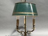 an antique brass table lamp with a green shade and two candles