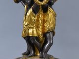 an image of a gold and black vase with a statue on top of it