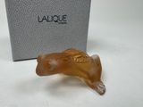 une photo représentant une figurine d'animal en verre posée devant une boîte