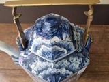 a blue and white teapot with a handle on a wooden table