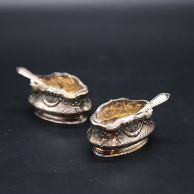 a pair of silver spoons sitting on top of a sauce dish