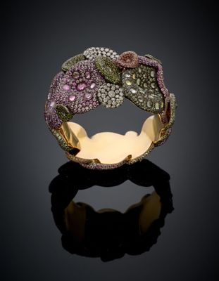 a close up of a gold ring with pink and green stones